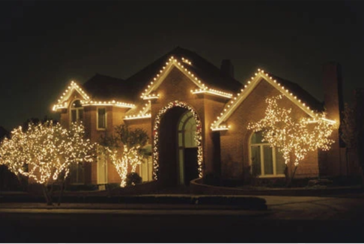 Brick home with lit trees and roofline holiday lighting