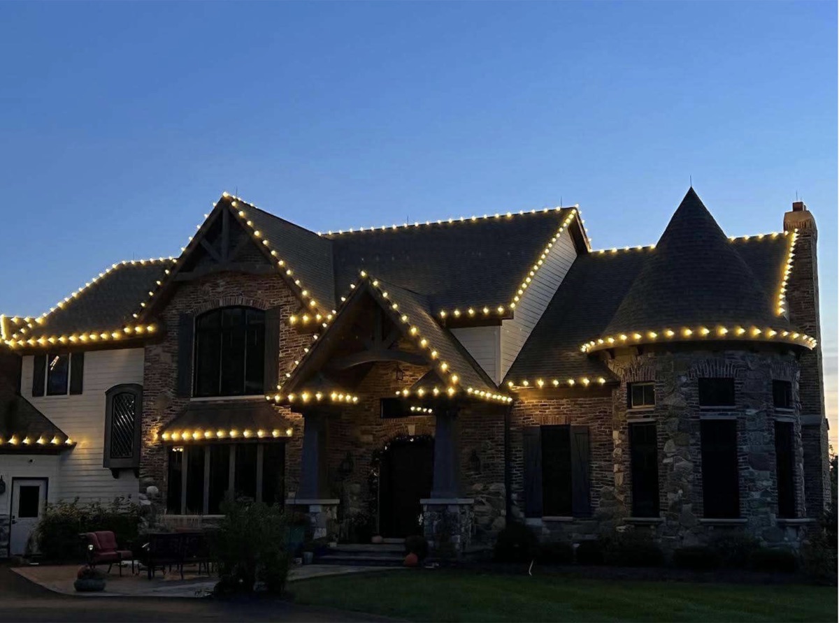 Stone home with roofline holiday lighting at dusk